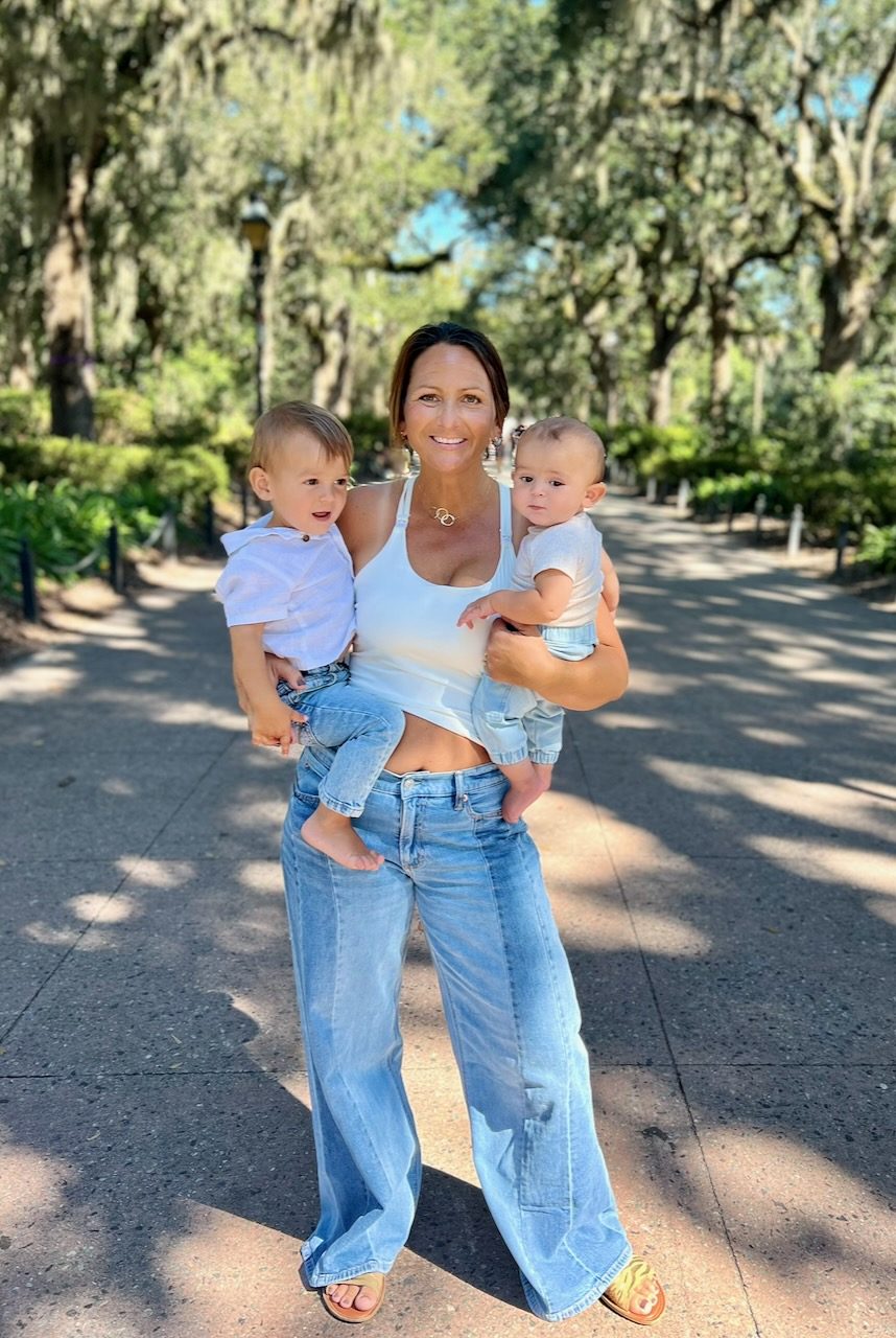 Danielle holding her two children on a sunlit path