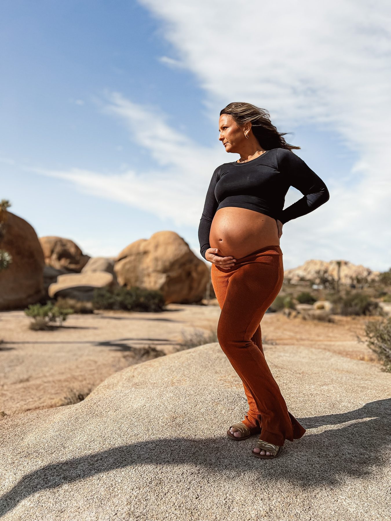 Expecting mother standing on desert rock under a wide sky